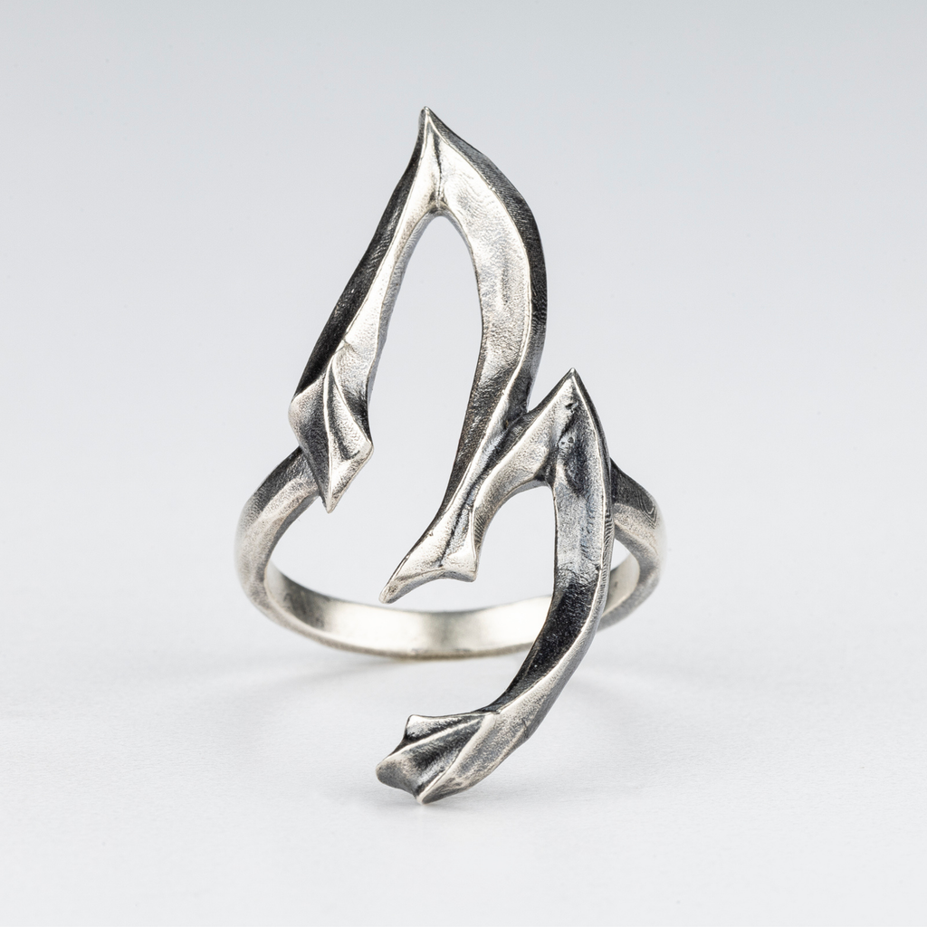 Close-up detail of the sculptural silver 3 Ring showing carved textures.