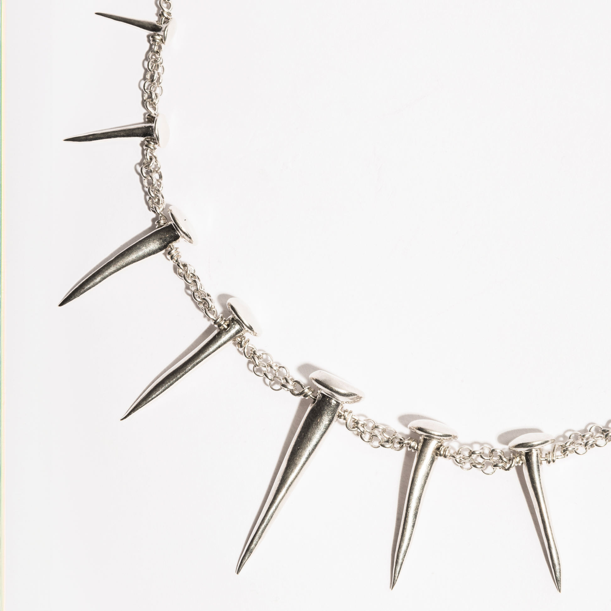 Detail view of the Nails Necklace by Sebamakes, handcrafted sterling silver necklace with nail-shaped spikes and textured metal links