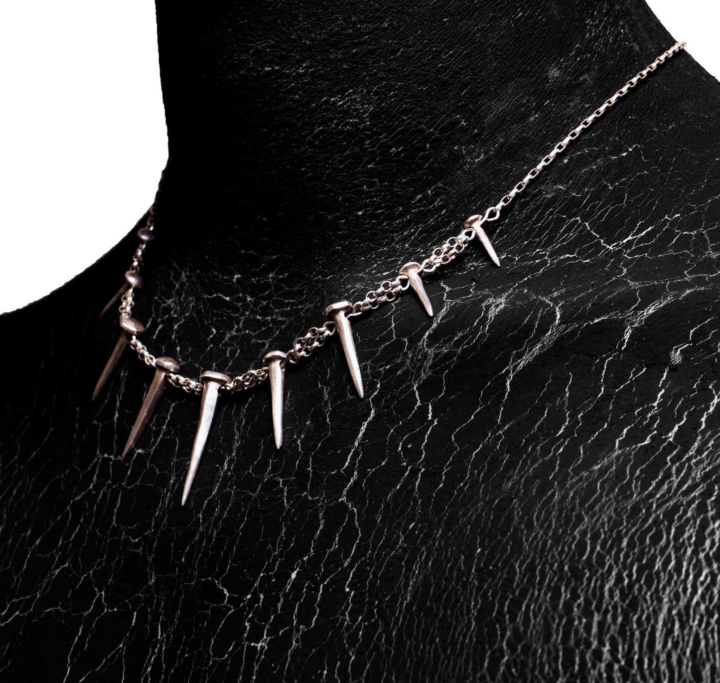 Angled worn view of the Nails Necklace by Sebamakes, sterling silver handcrafted necklace with nail-shaped spikes and raw textured finish.