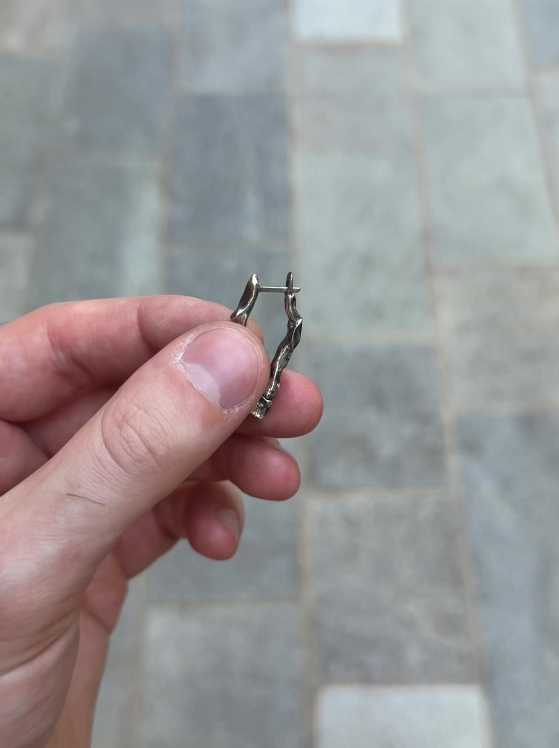 Long Ridge drop earrings held in hand to highlight artisanal proportions and finish.