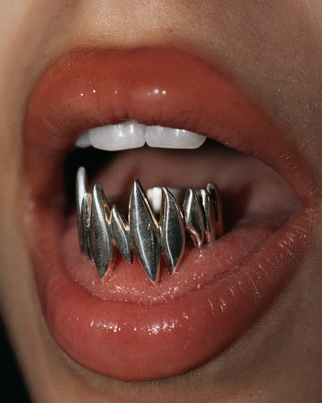 Close-up of lips with the silver Splinter Ring worn like teeth.