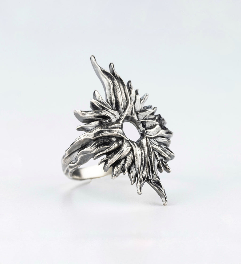 Silver ring with an organic textured design and central opening, angled view handcrafted by sebamakes