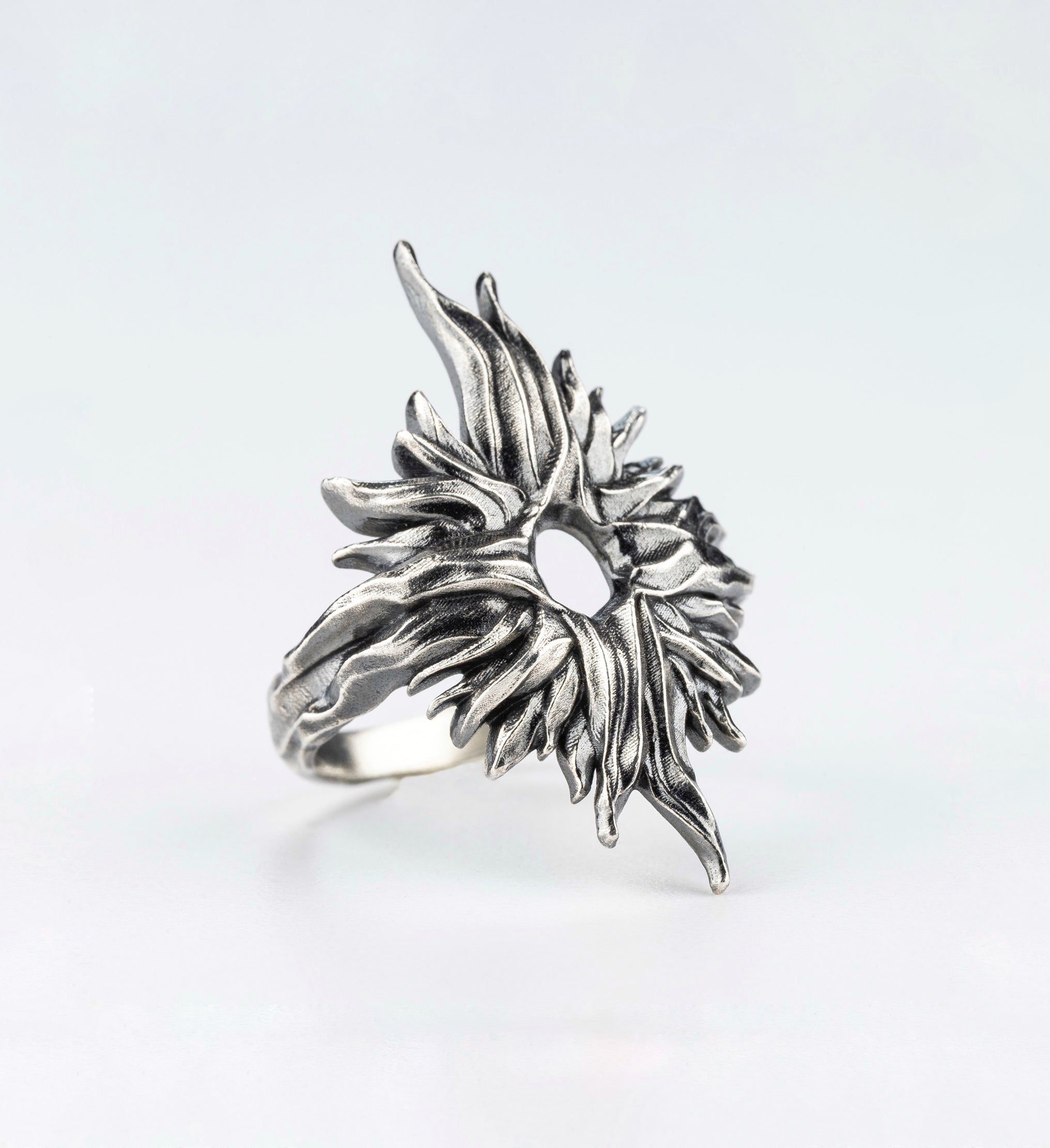 Silver ring with an organic textured design and central opening, angled view handcrafted by sebamakes
